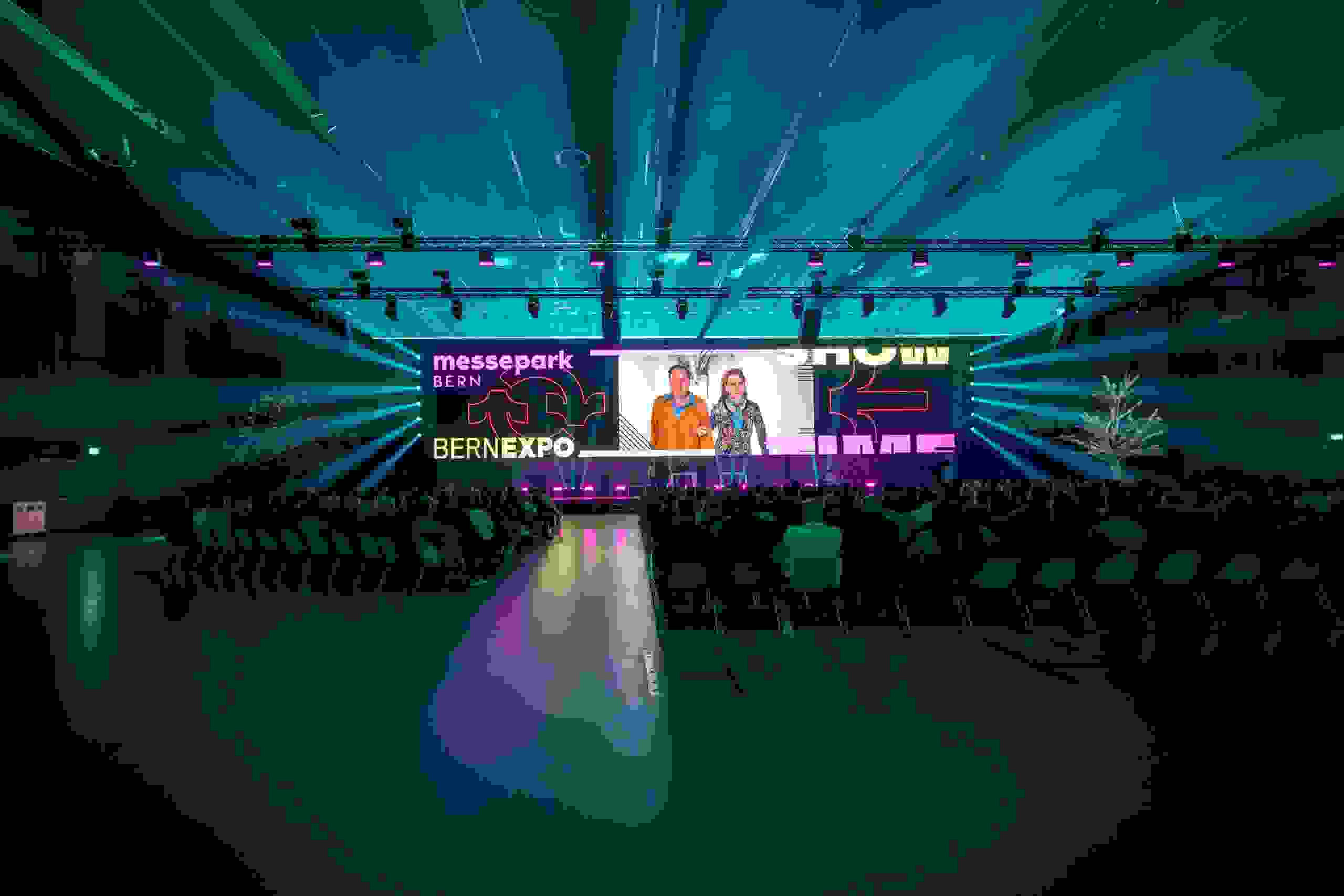 Grosses Publikum vor LED-Wand in der Festhalle – beeindruckende Live Kommunikation mit multimedialer Inszenierung. Schauspieler, Schauspielerin, markenerlebnis, Brand Experience, Bernexpo, Festhalle, Dekoration, Eröffnungsfeier, mitarbeiteranlass, Showtime, Corporate-Event, eventagentur bern, Bernexpo, Bühne, Live Kommunikation, LED-Show, Corporate Event