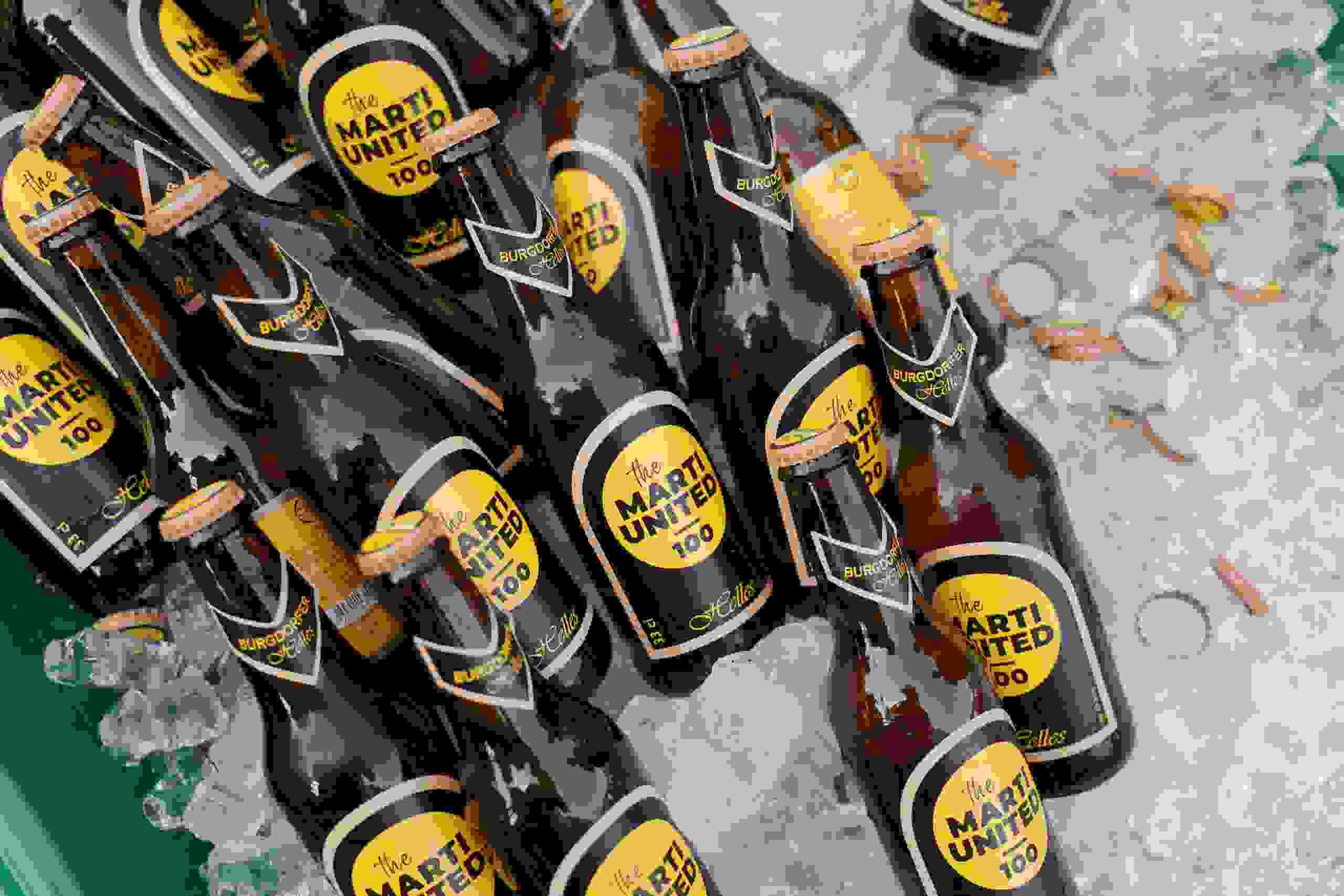 Gebrandete Bierflaschen „Marti United 100“ im Eis beim Firmenjubiläum. Eventcatering, Corporate Design, Branding Marti AG, Firmenjubiläum, Live-Entertainment, Showact, Markenerlebnis, Brand Experience, Mitarbeiteranlass, Live Kommunikation, Corporate-Event, eventplanung, Jubiläumsfeier, Mitarbeiteranlass, Teamevent, 100 Jahre