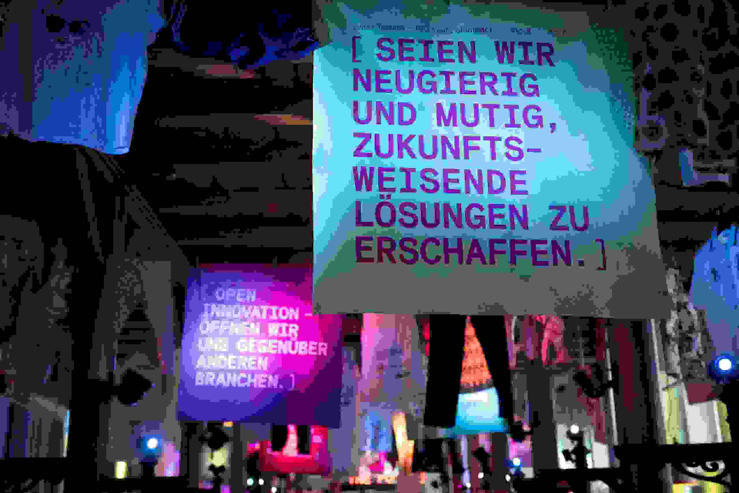 Inspirierende Statements wie „Seien wir neugierig und mutig“ auf Stoffbannern – visuelle Kommunikation für Innovationsgeist in der Textilindustrie. Innovation, Zukunftsvision, Textilbranche, Designkommunikation, Swiss Textiles 150 Jahre, reingewaschen, markenerlebnis, Brand Experience, Riithalle Zürich, Dekoration, jubiläumsfeier, mitarbeiteranlass, live kommunikation, Zukunftsorientiert, neu
