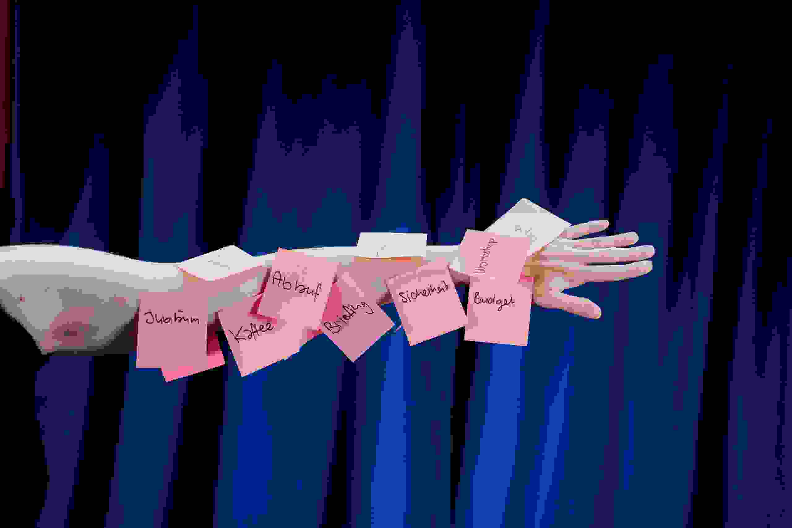 Arm mit Rosa Post-It's vor dunkelblauem Hintergrund.  kreative Deko, visuelles Storytelling für Veranstaltungen, Markenerlebnis, Brand Experience, Eventplanung, Publicevent, Eventagentur Bern, Technik, Beleuchtung, Live Kommunikation