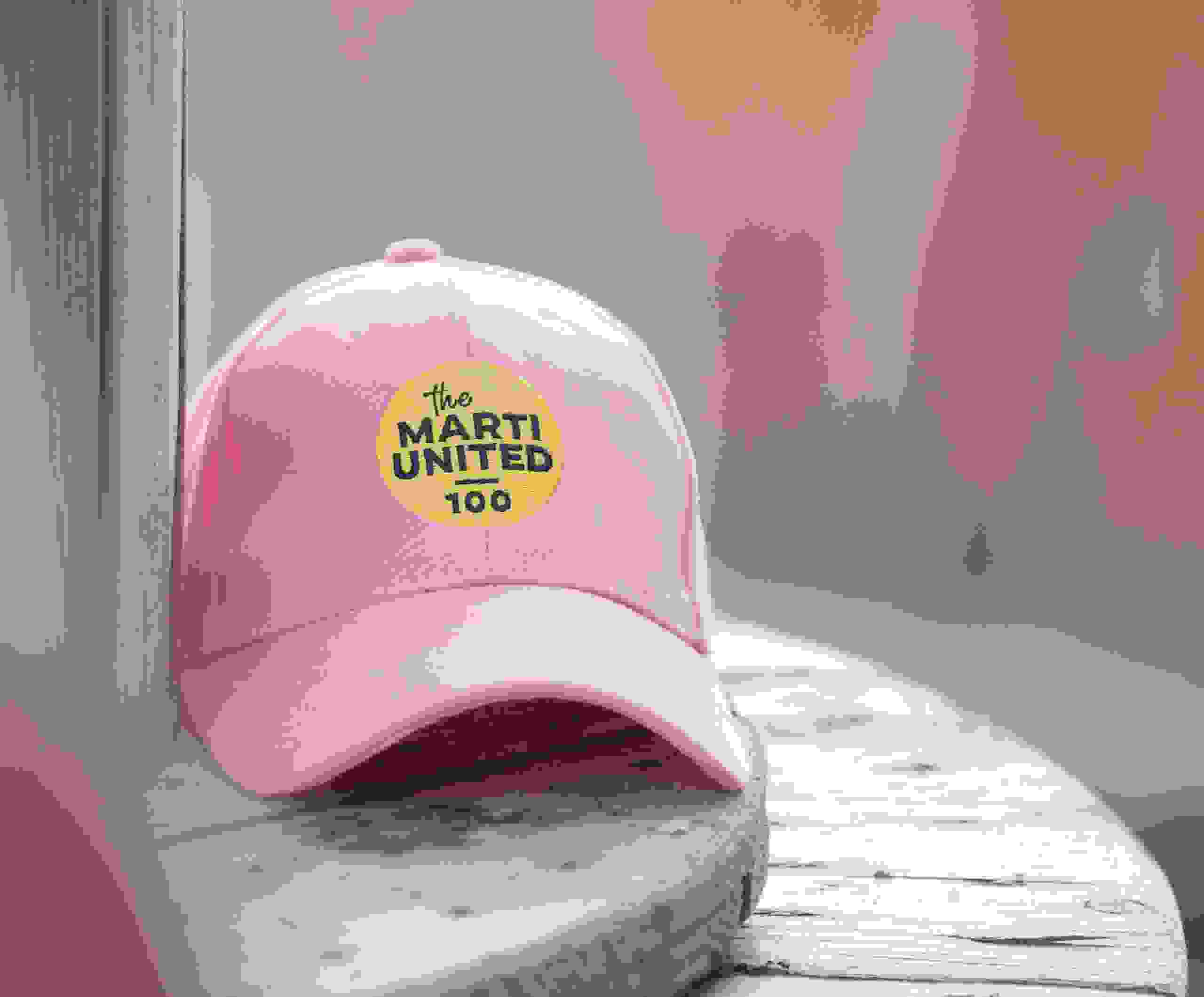 Rosa Cap mit dem Marti United 100 Logo als Merchandise-Artikel zum Firmenjubiläum. Marti United 100, Merchandise, Cap, Jubiläumsgeschenk, Event-Souvenir, Branding, Firmenevent, Give Away, Markenerlebnis, Brand Experience, Mitarbeiteranlass, Live Kommunikation, Corporate-Event