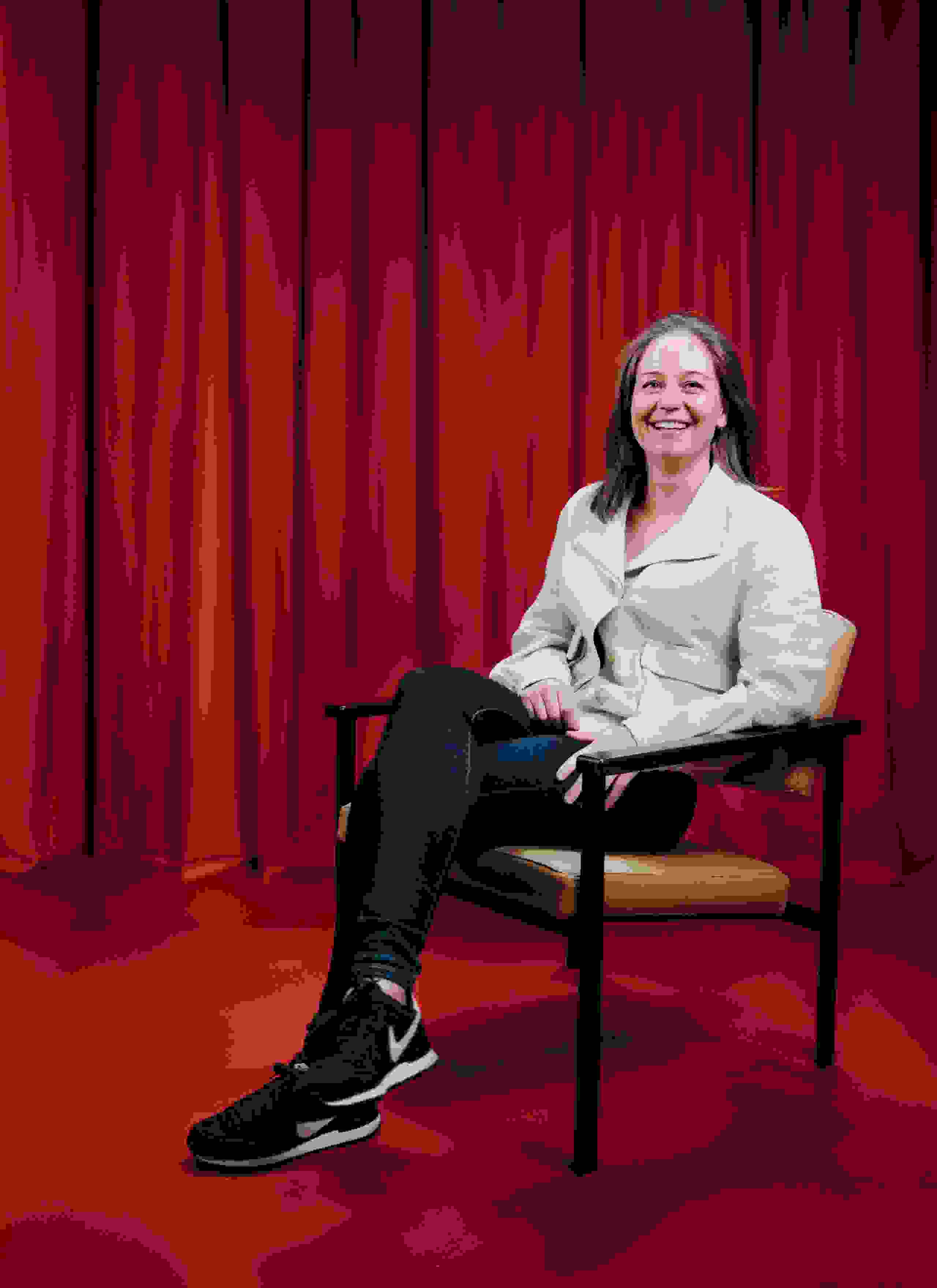 Mitarbeiterin Carola Kunz der Live Kommunikations Agentur evenjo sitzt entspannt auf einem Stuhl vor rotem Hintergrund, modernes Portraitfoto, live kommunikation, Corporate-Event, Eventagentur bern, eventplanung, firmenevents, teamevents bern, jubiläumsfeier, networking anlass, mitarbeiteranlass,   Finanzfachfrau, Treuhänderin, evenjo-Team