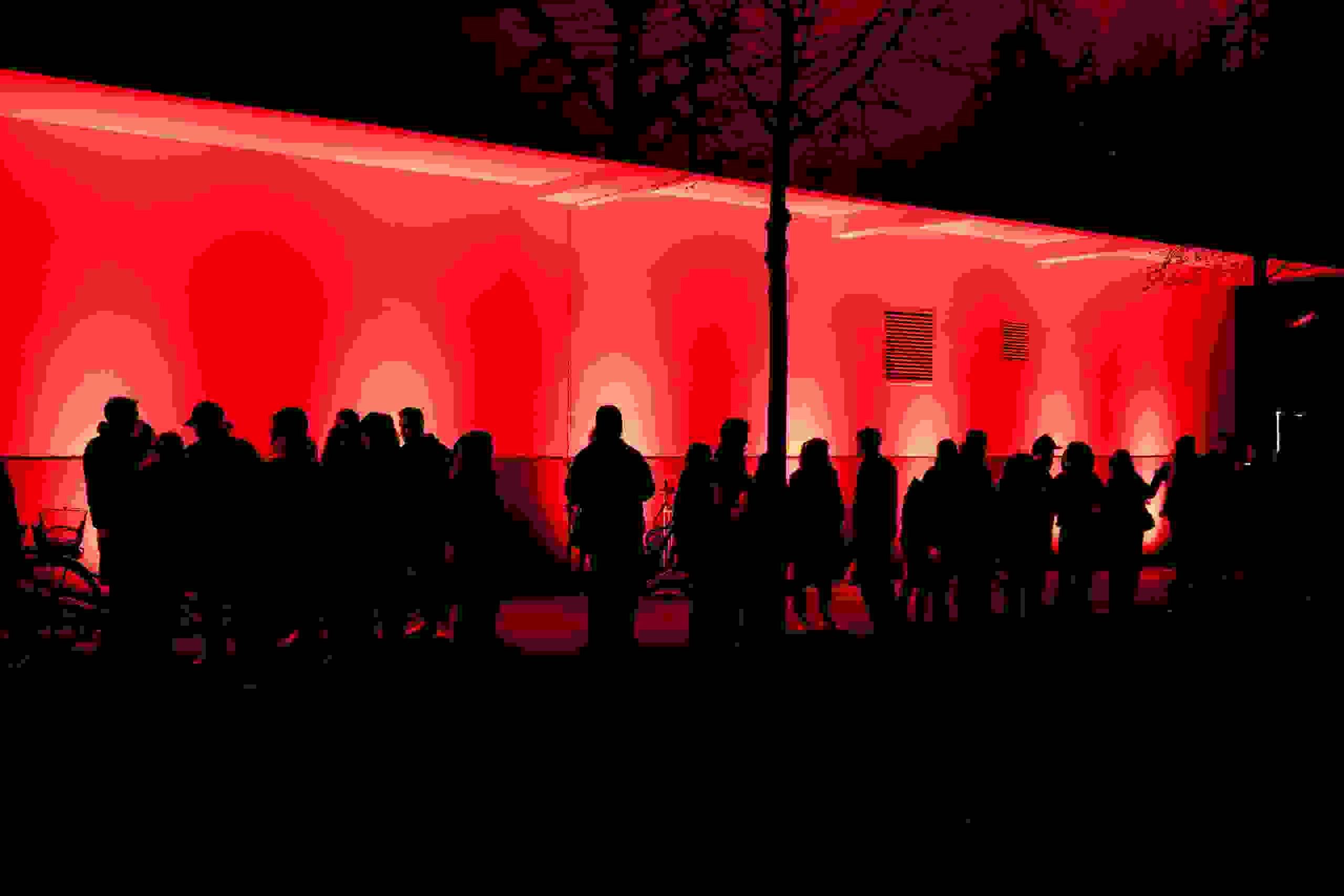 Besucher:innen vor rot beleuchteter Wand während der Museumsnacht in Bern – eindrucksvolle Lichtinszenierung. Stadt Bern, Lichtinstallation, Besucher, rote Beleuchtung, nächtliches Event, Eventstimmung, Eventagentur Bern, Live Kommunikation, Corporate-Event, eventplanung, Verein Museen Bern, Publicevent