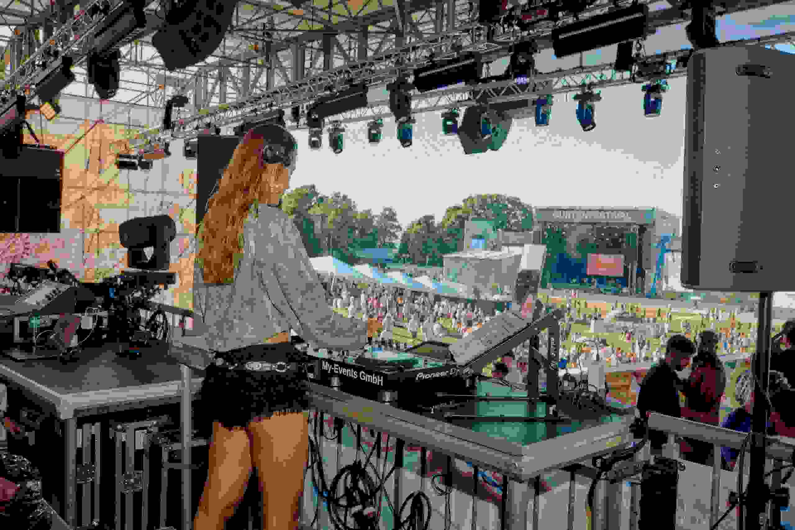 Eine DJane steht auf der Supermercado-Bühne des Gurtenfestivals in Bern und legt Musik auf. Von der Bühne aus sieht man das Publikum und die große Hauptbühne im Hintergrund.