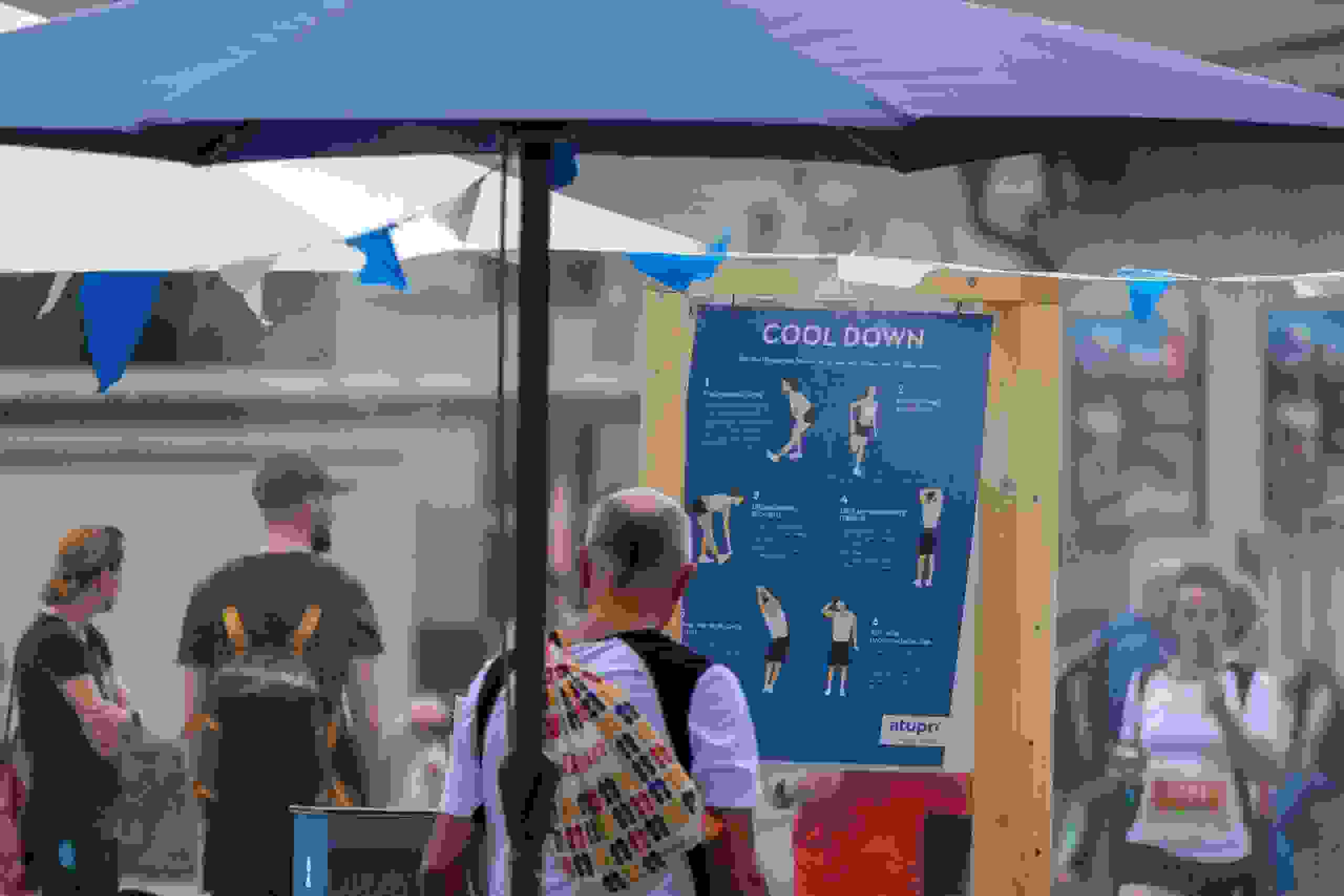 Teilnehmer studiert Cool-Down-Übungen am Atupri Healthbox Stand bei Outdoor-Event mit Fokus auf Bewegung und Gesundheit. Atupri Healthbox, Cool Down, Gesundheitsevent, Fitnessübungen, Outdoor-Stretching, Bewegung fördern, live kommunikation, Corporate-Event, Eventagentur bern, eventplanung, firmenevents, teamevents bern, jubiläumsfeier, networking anlass, mitarbeiteranlass, Technik, Public Events, Sport und Entertainment Events, markenerlebnis, Brand Experience
