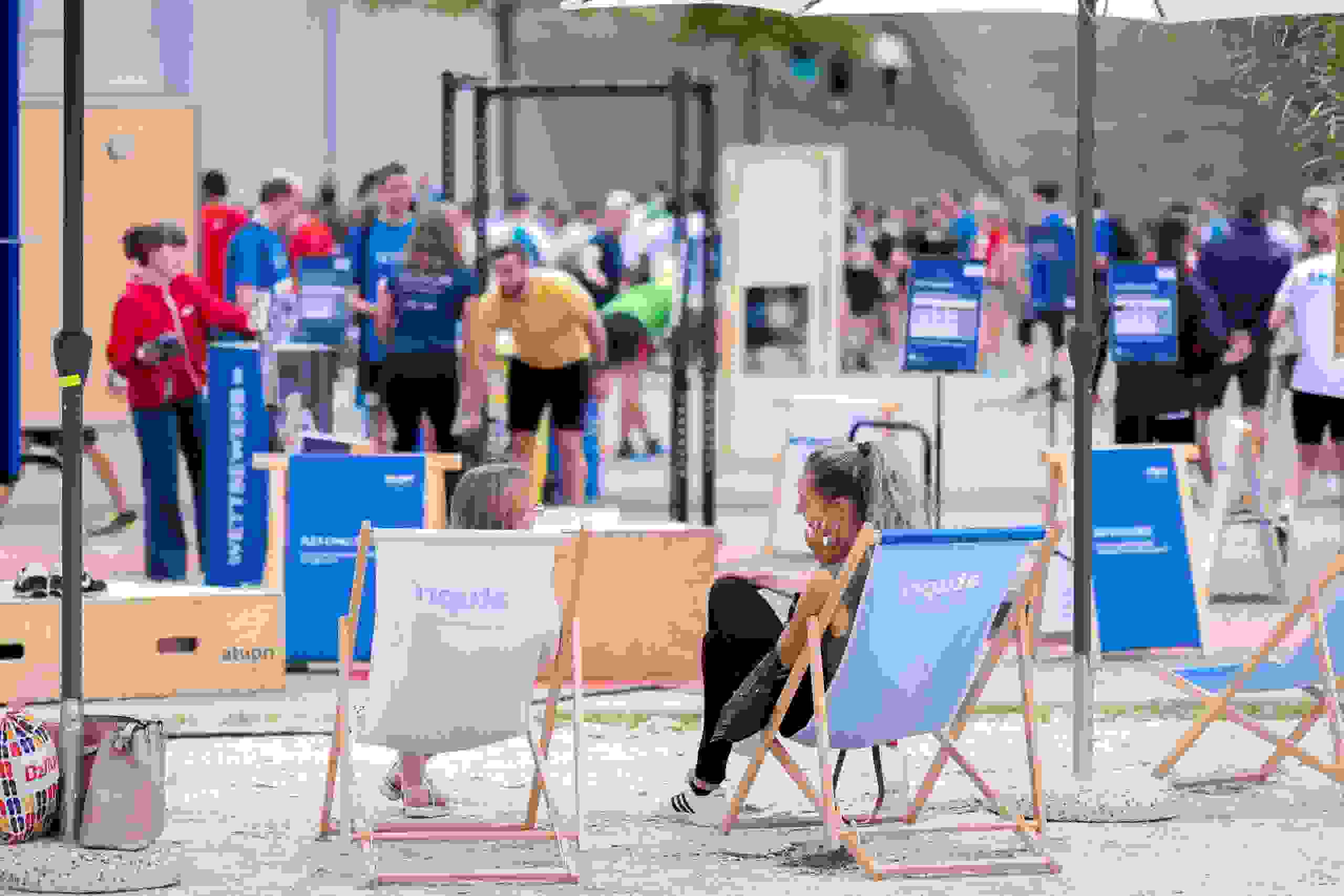 Zwei Teilnehmerinnen entspannen sich nach dem Workout im Liegestuhlbereich der Atupri Healthbox beim Fitness-Event. Atupri Healthbox, Fitnesspause, Entspannung, Liegestühle, Gesundheitsevent, Wohlfühlen, live kommunikation, Corporate-Event, Eventagentur bern, eventplanung, firmenevents, teamevents bern, jubiläumsfeier, networking anlass, mitarbeiteranlass, Technik, Public Events, Sport und Entertainment Events, markenerlebnis, Brand Experience