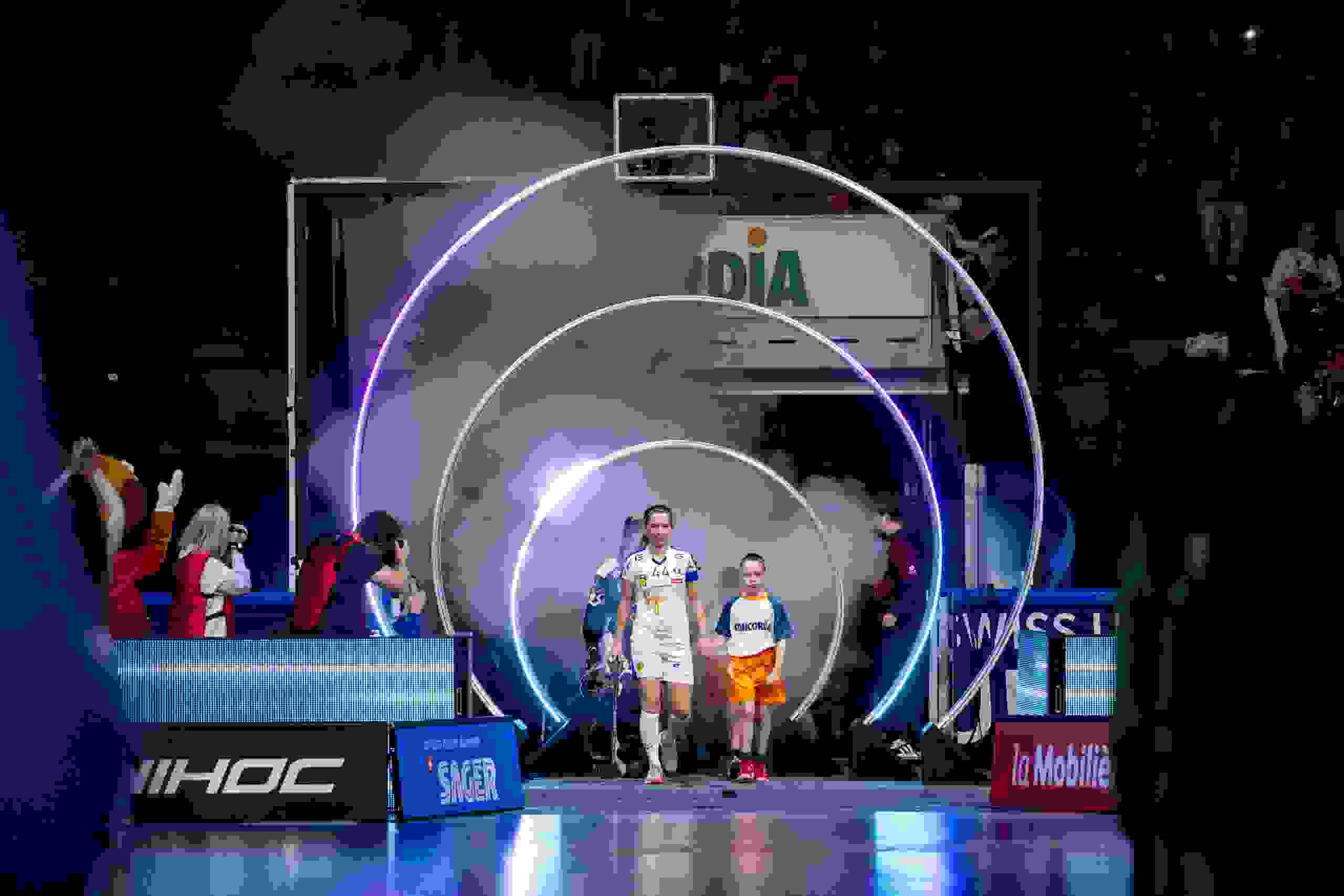 Spielerinnen des Unihockey Superfinals betreten mit Kindern und unter Lichteffekten das Spielfeld, beeindruckender Einlaufmoment. Einlaufshow, Lichteffekte, Spielerinnen, Emotionen, Sportevent Schweiz, Floorball, live kommunikation, Corporate-Event, Eventagentur bern, eventplanung, firmenevents, teamevents bern, jubiläumsfeier, networking anlass, mitarbeiteranlass, evenjo-Team, Technik, Public Events, Sport und Entertainment Events, markenerlebnis, Brand Experience, Corporate-Event, Lichtshow, Eröffnungsshow