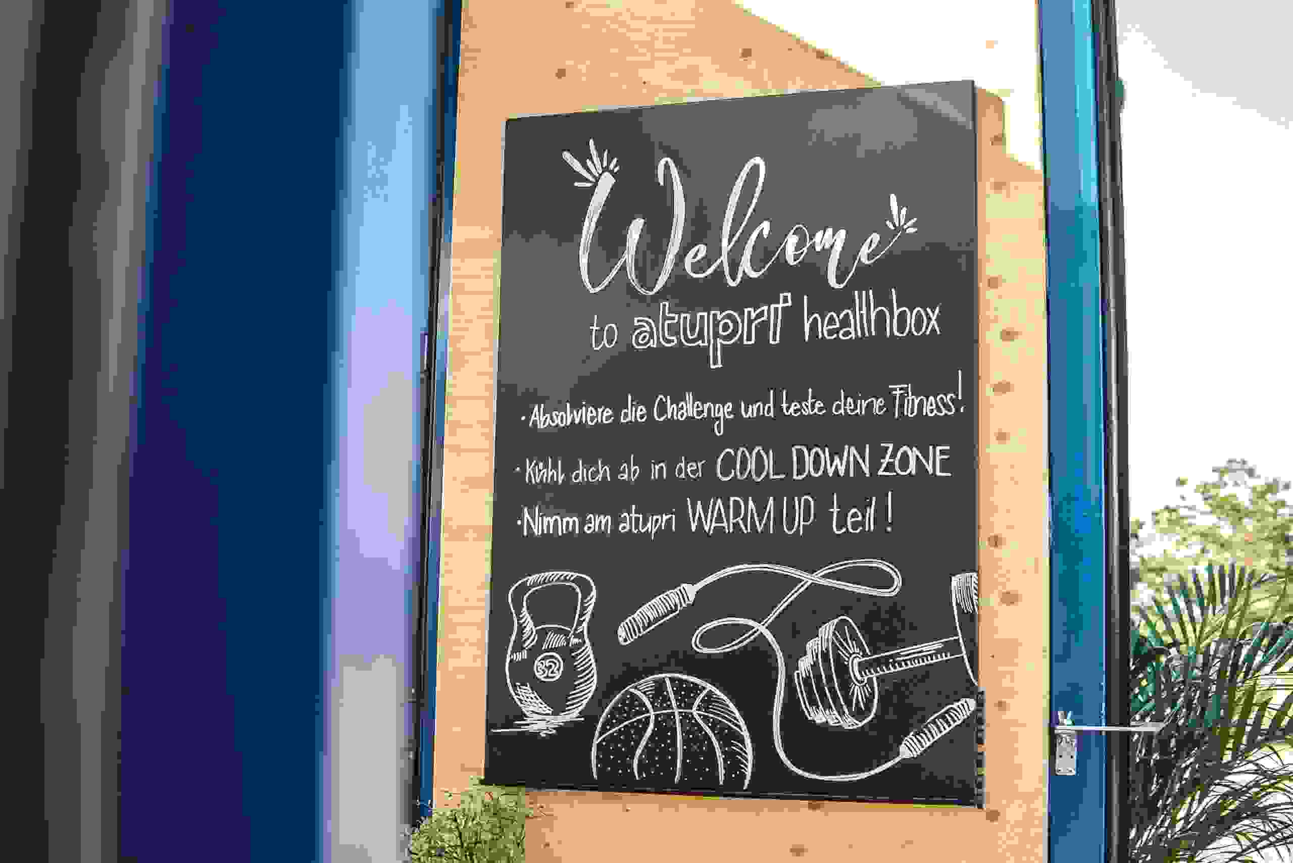 Willkommenstafel mit Aufrufen zur Fitness-Challenge, Cool-Down-Zone und Warm-up bei der Atupri Healthbox. Eventbegrüssung, Fitness-Challenge, Warm-up, Cool Down, Bewegung motivieren, live kommunikation, Corporate-Event, Eventagentur bern, eventplanung, firmenevents, teamevents bern, jubiläumsfeier, networking anlass, mitarbeiteranlass, Technik, Public Events, Sport und Entertainment Events, markenerlebnis, Brand Experience