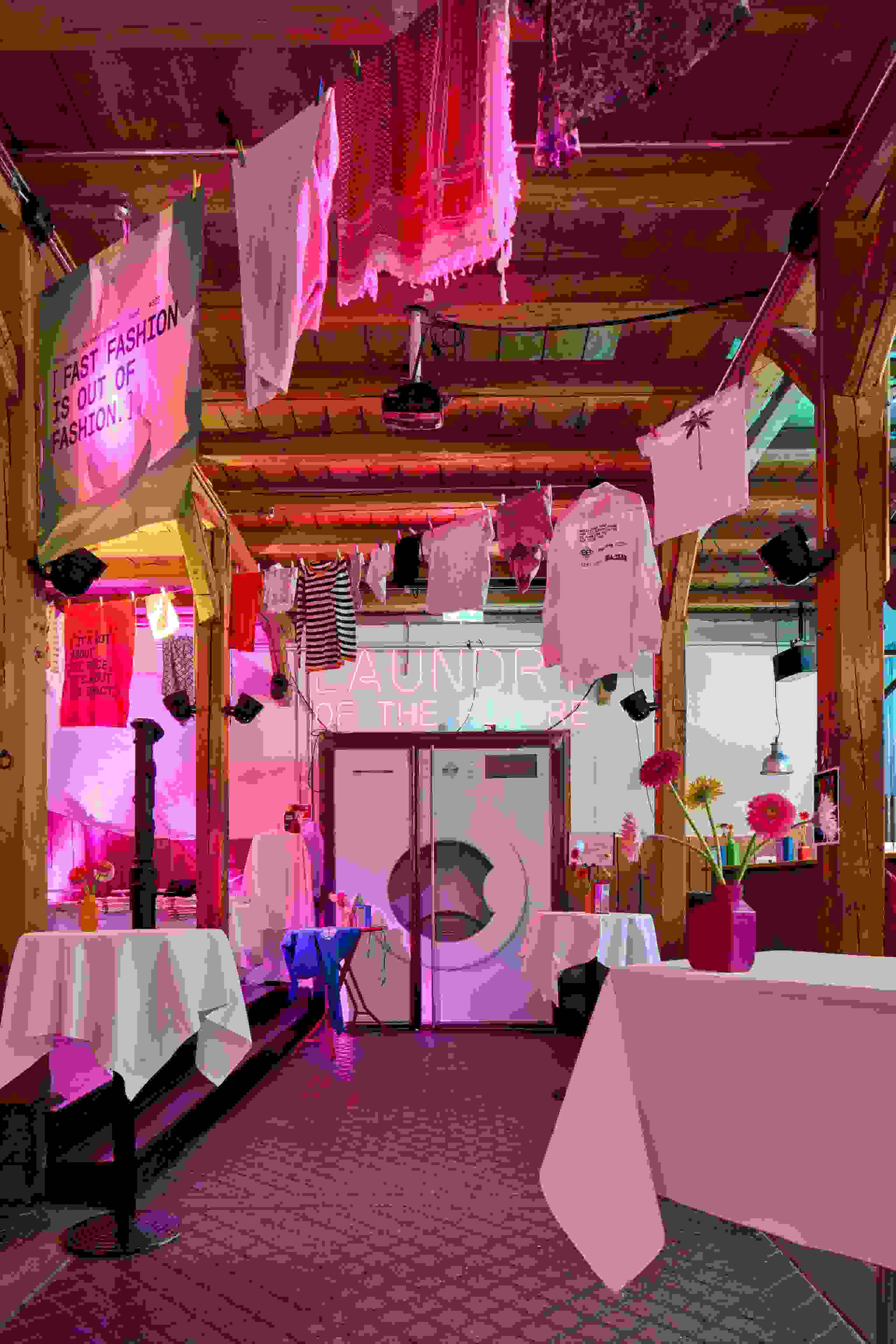 Inszenierung „Laundry of the Future“ mit Neon-Schriftzug und aufgehängten Textilien – visionärer Blick auf die Textilbranche von morgen. Zukunftsdesign, Textilbranche, Installationskunst, Innovationsshow, Waschmaschinen-Event, markenerlebnis, Brand Experience, Riithalle Zürich, Dekoration, jubiläumsfeier, mitarbeiteranlass, live kommunikation