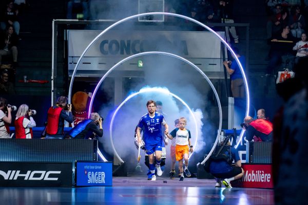 Spieler des Unihockey Superfinals betreten mit Kindern und unter Lichteffekten das Spielfeld, beeindruckender Einlaufmoment. Einlaufshow, Lichteffekte, Spielerinnen, Emotionen, Sportevent Schweiz, Floorball, live kommunikation, Corporate-Event, Eventagentur bern, eventplanung, firmenevents, teamevents bern, jubiläumsfeier, networking anlass, mitarbeiteranlass, evenjo-Team, Technik, Public Events, Sport und Entertainment Events, markenerlebnis, Brand Experience, Corporate-Event, Lichtshow, Eröffnungsshow