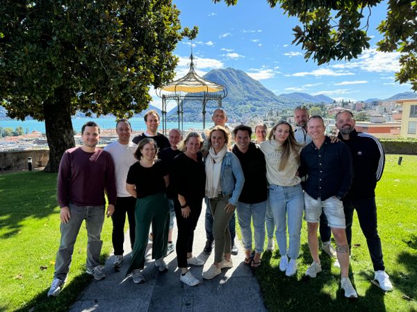 Gruppenfoto des evenjo-Teams im Park mit Seeblick und Pavillon. Eventagentur Bern, Teamspirit, Teamevent, Betriebsausflug, Markenerlebnis, Brand Experience, Eventplanung, Publicevent, Eventagentur Bern, Corporate-Event, Mitarbeiteranlass, Mitarbeiter:innen-Anlass, Live Kommunikation, networking Anlass, Ausflug, Teambuilding