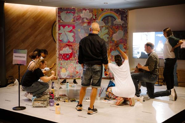 Team malt gemeinsam ein buntes Kunstwerk bei einem Kreativ-Workshop. Teamevent, Mitarbeiterbindung, kreative Live-Kommunikation, Markenerlebnis, Brand Experience, Eventplanung, Publicevent, Eventagentur Bern, Technik, Live Kommunikation, networking anlass, Mitarbeiteranlass, Mitarbeiter:innen-anlass, Jubiläumsfeier, Weihnachstfeier firma, Corporate-Event