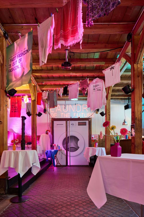 Inszenierung „Laundry of the Future“ mit Neon-Schriftzug und aufgehängten Textilien – visionärer Blick auf die Textilbranche von morgen. Zukunftsdesign, Textilbranche, Installationskunst, Innovationsshow, Waschmaschinen-Event, markenerlebnis, Brand Experience, Riithalle Zürich, Dekoration, jubiläumsfeier, mitarbeiteranlass, live kommunikation