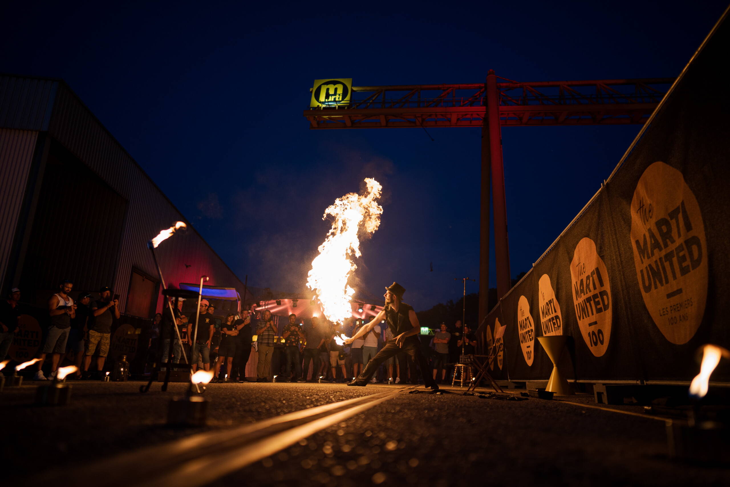 crossmediale-kommunikation-jubilaeum-marti-ag-8.jpg Feuerkünstler begeistert das Publikum mit Feuershow beim Marti United 100 Firmenjubiläum. Marti United 100, Feuershow, Artistik, Nachtprogramm, Firmenjubiläum, Live-Entertainment, Showact, Markenerlebnis, Brand Experience, Mitarbeiteranlass, Live Kommunikation, Corporate-Event, eventplanung, Jubiläumsfeier, Mitarbeiteranlass, Teamevent, 100 Jahre Marti AG, Festival