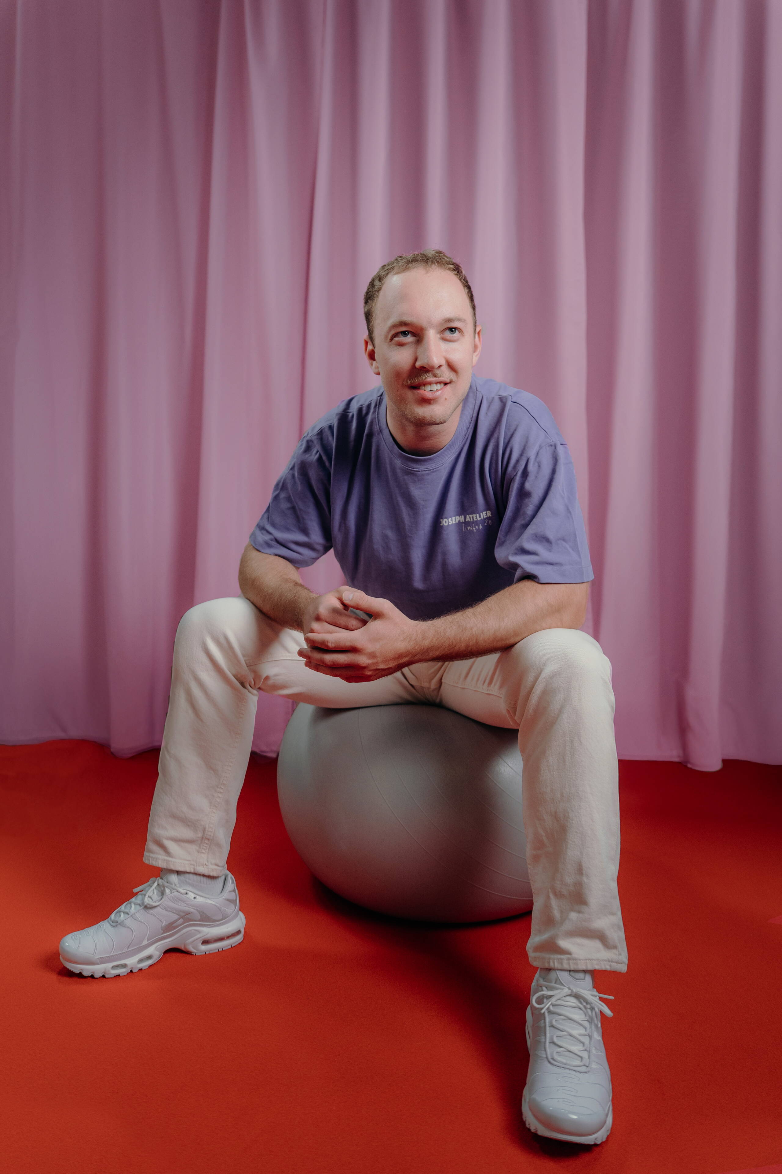 thierry-riedo.jpg Mitarbeiter Thierry Riedo der Live Kommunikations Agentur evenjo auf einem Gymnastikball vor rosa Vorhang. live kommunikation, Corporate-Event, Eventagentur bern, eventplanung, firmenevents, teamevents bern, jubiläumsfeier, networking anlass, mitarbeiteranlass, evenjo-Team, Technik, Junior Projektleitung, Beratung