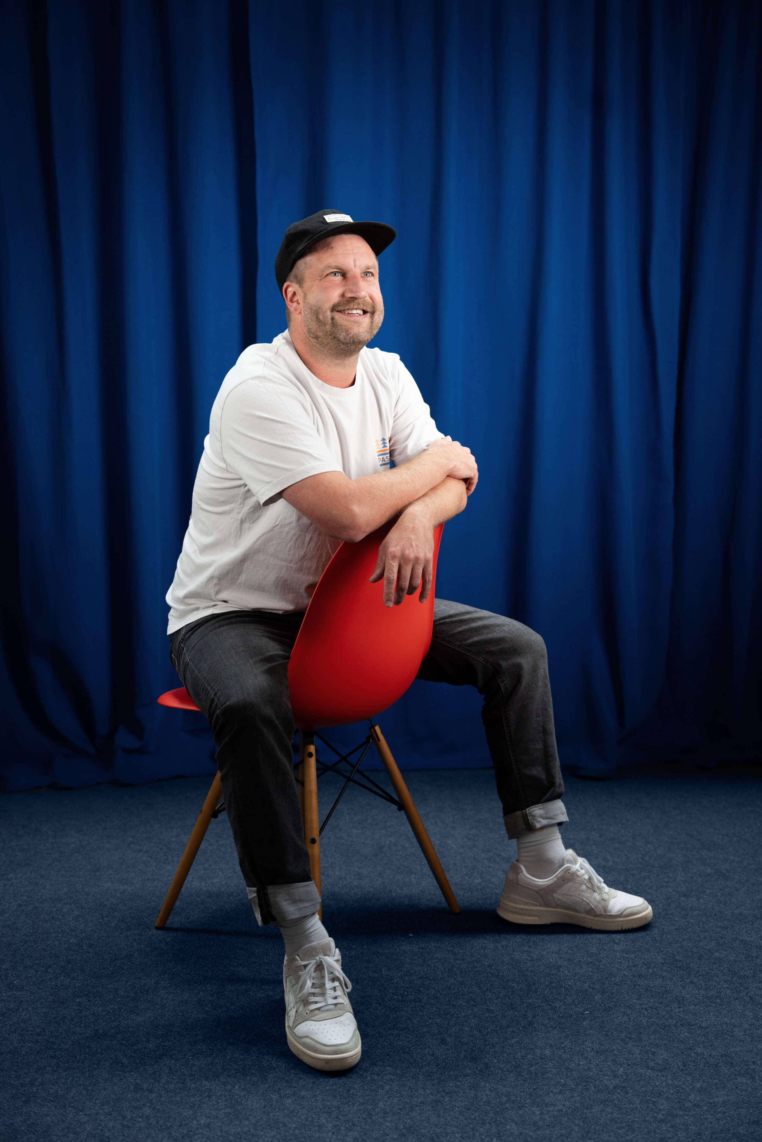 Mitarbeiter Basil Walther der Live Kommunikations Agentur evenjo mit schwarzem T-Shirt vor blauem Hintergrund, Porträt für Teamvorstellung, live kommunikation, Corporate-Event, Eventagentur bern, eventplanung, firmenevents, teamevents bern, jubiläumsfeier, networking anlass, mitarbeiteranlass, Dekoration, Polydesigner 3D, evenjo-Team