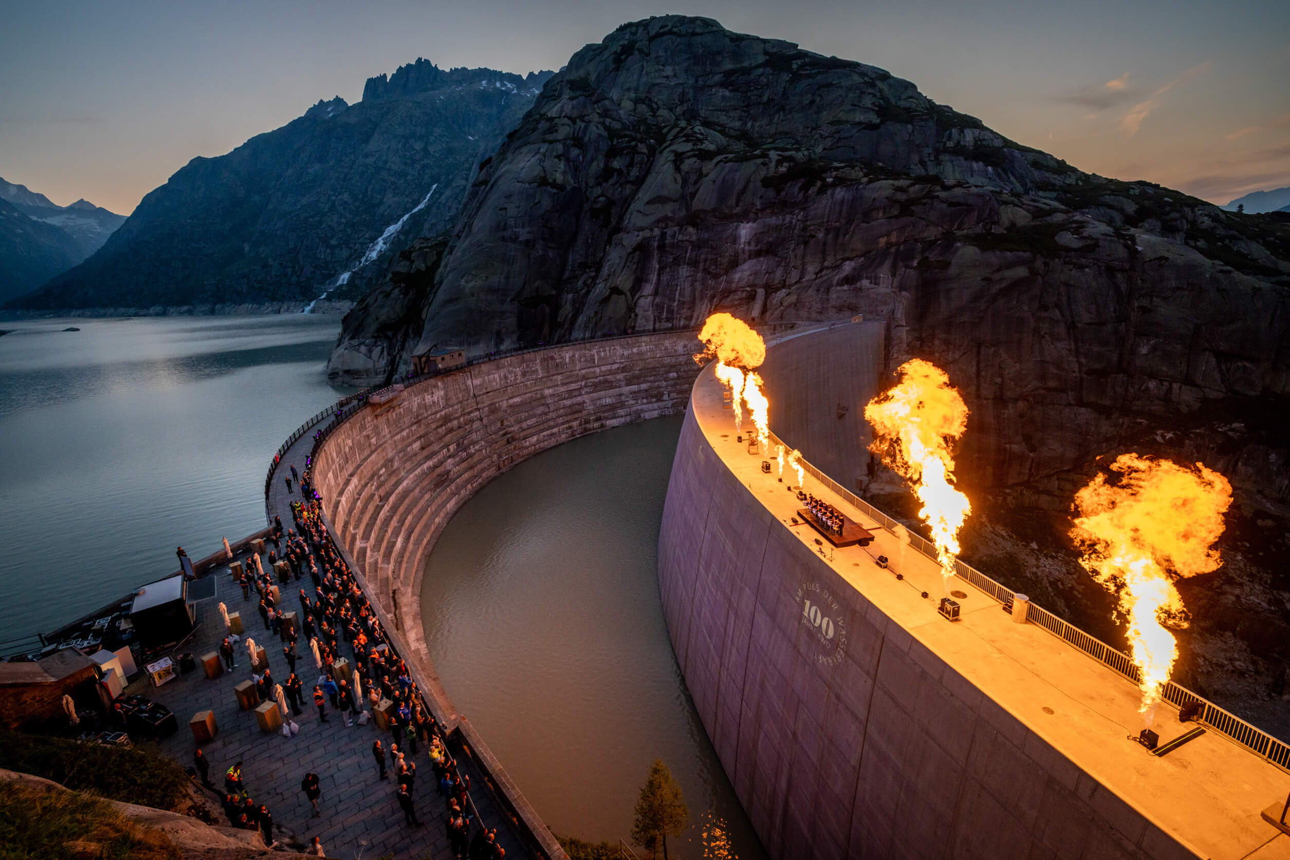 Feuerinszenierung auf der Staumauer bei Sonnenuntergang – spektakuläres Highlight der 100 Jahre KWO Jubiläumsfeier.