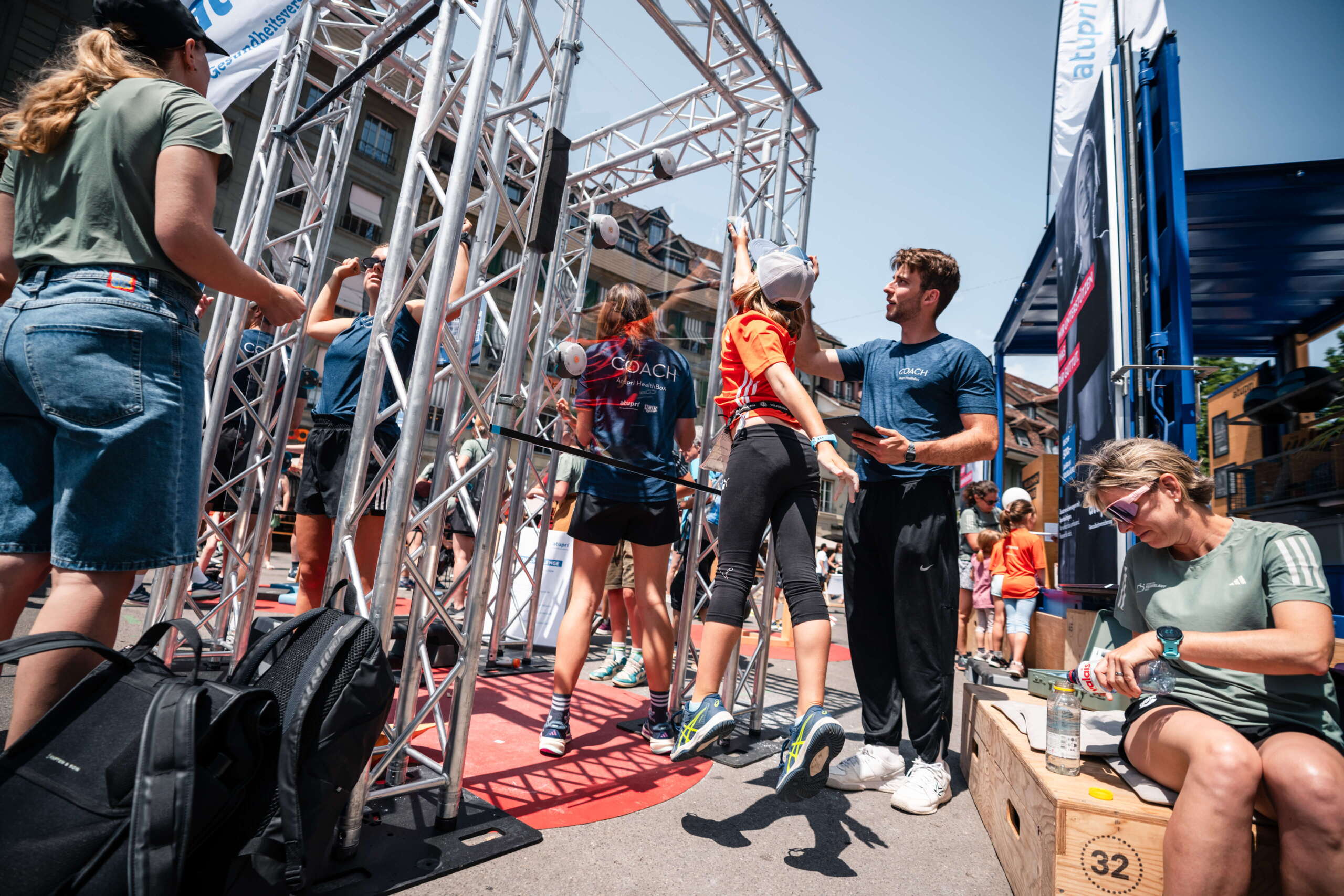 evenjo-ag-eventagentur-bern-atupri-healthbox-25.jpg Mädchen wird bei Fitnessparcours der Atupri Healthbox angeleitet, während Coaches unterstützen und beobachten. Kinderfitness, Coach-Betreuung, Gesundheitsförderung, Bewegungsförderung, Parcours, live kommunikation, Corporate-Event, Eventagentur bern, eventplanung, firmenevents, teamevents bern, jubiläumsfeier, networking anlass, mitarbeiteranlass, Technik, Public Events, Sport und Entertainment Events, markenerlebnis, Brand Experience