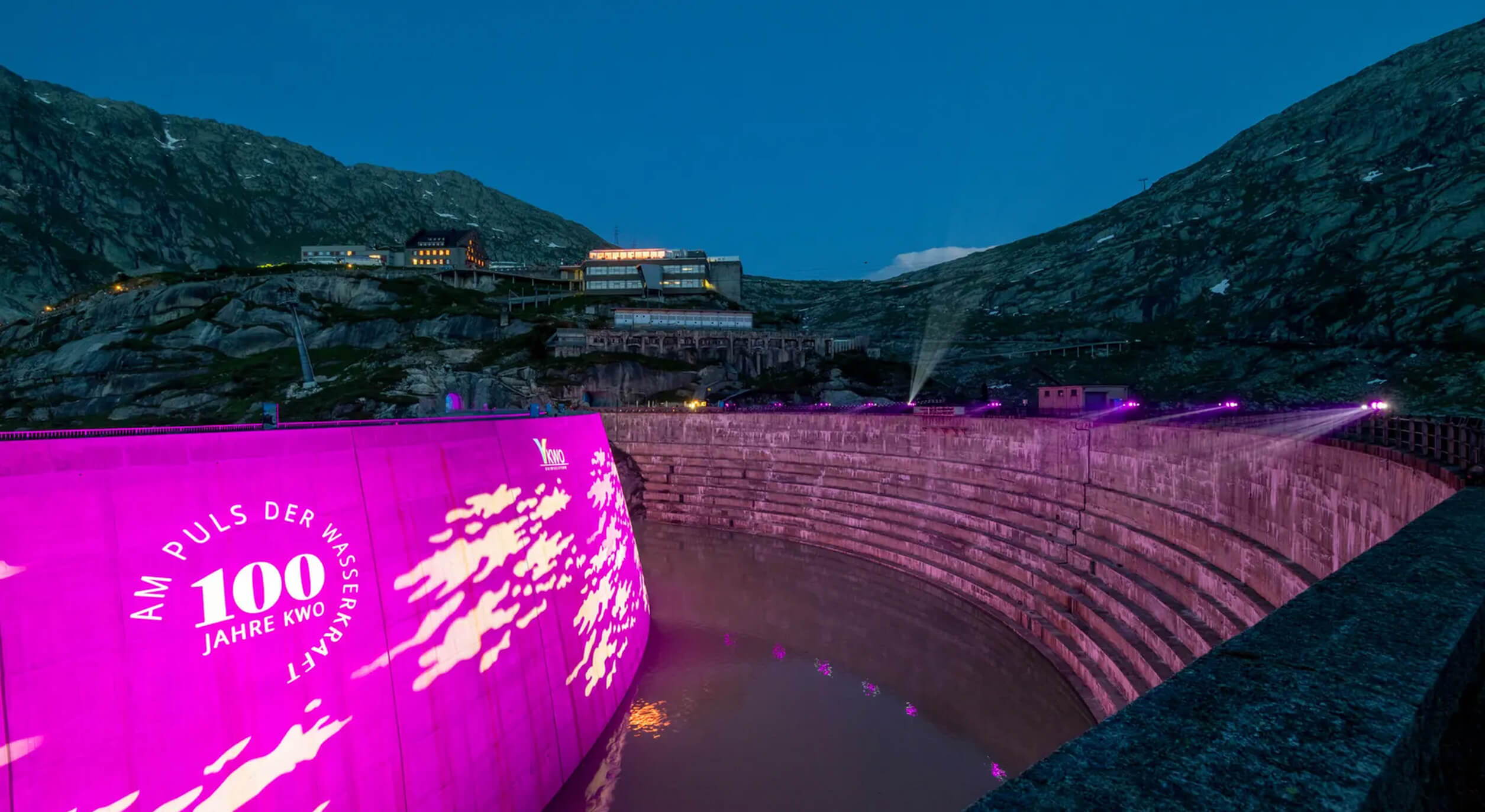 Pink beleuchtete Staumauer mit Projektion «100 Jahre KWO» – visuelles Highlight eines einzigartigen Jubiläumsevents in den Alpen.