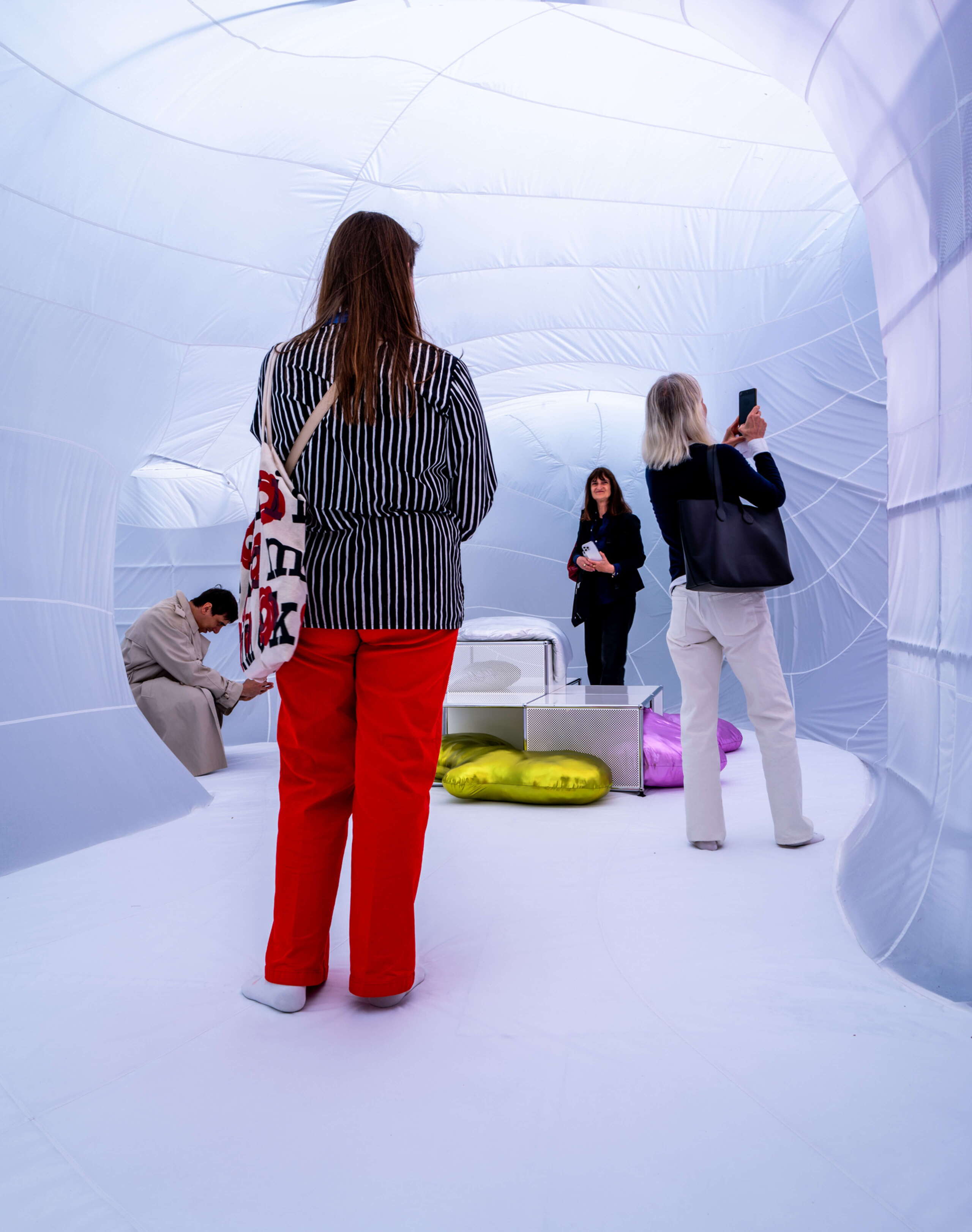 Besucher:innen bewegen sich barfuss durch die immersive USM-Installation am Fuorisalone der Milan Design Week in Milano. Der weiche, textile Raum wirkt wie eine begehbare Wolke und schafft mit diffusem Licht und organischen Formen eine ruhige, fast schwerelose Atmosphäre.