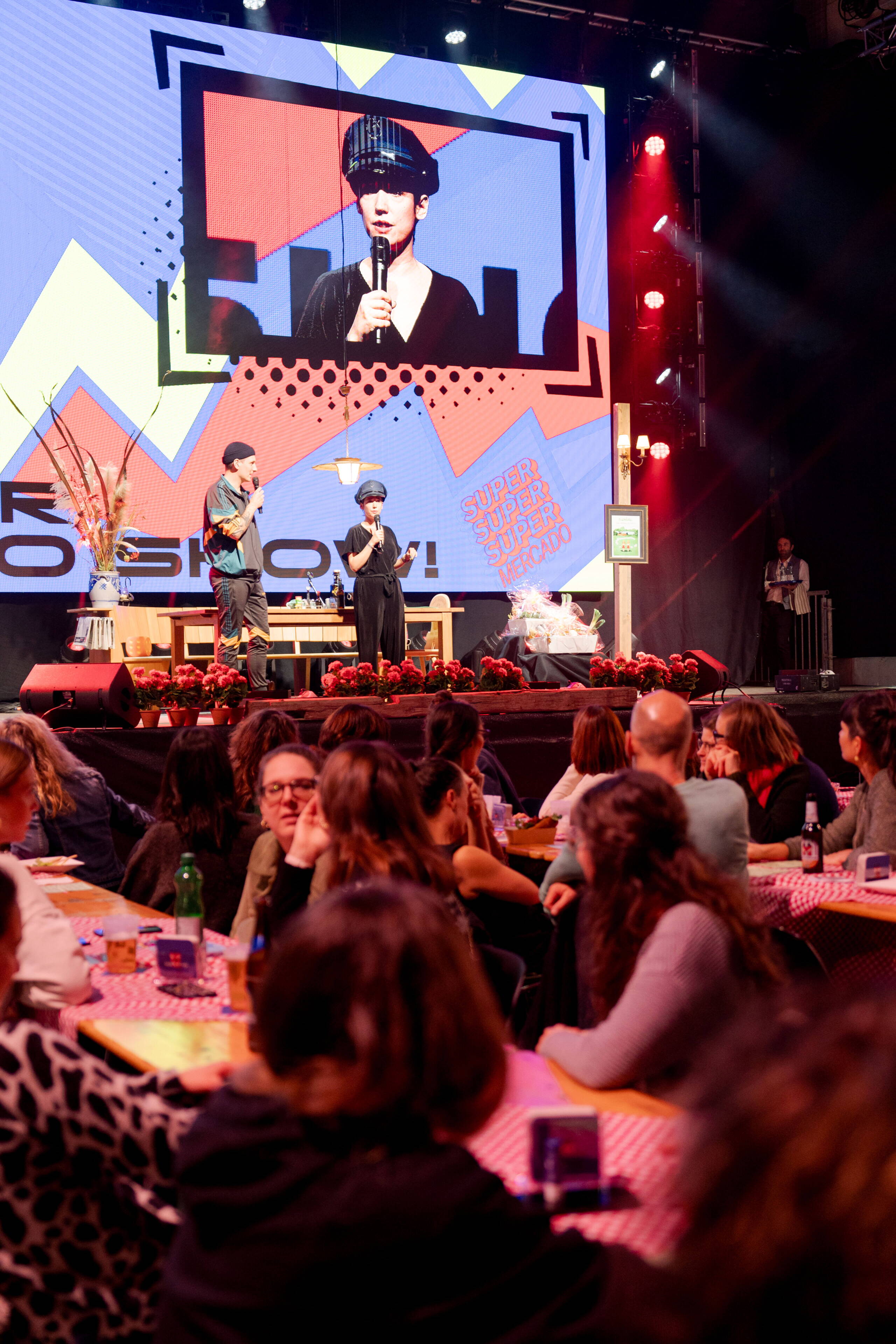 evenjo_gurtenfestival_superlotto_publicevent_bern-5.jpg Zwei Moderatoren auf der Bühne vor kreativem Bühnenbild – unterhaltsames Programm für ein grosses, aktives Publikum. Live-Show, Moderation, Supermercado, Publikumsinteraktion, Kulturprogramm, eventagentur bern, Eventtechnik, live kommunikation, markenerlebnis, Lotto, Gülsha Adilji,