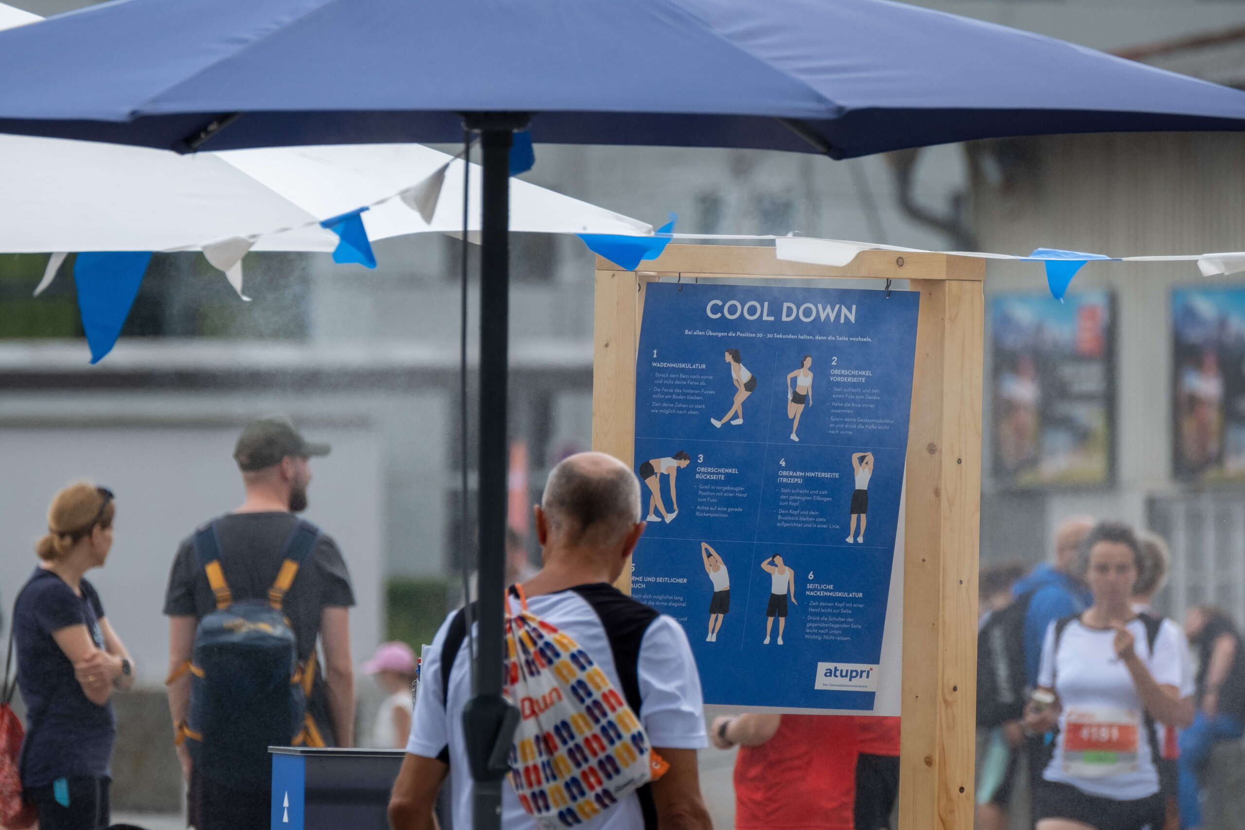 evenjo-ag-eventagentur-bern-atupri-healthbox-17.jpg Teilnehmer studiert Cool-Down-Übungen am Atupri Healthbox Stand bei Outdoor-Event mit Fokus auf Bewegung und Gesundheit. Atupri Healthbox, Cool Down, Gesundheitsevent, Fitnessübungen, Outdoor-Stretching, Bewegung fördern, live kommunikation, Corporate-Event, Eventagentur bern, eventplanung, firmenevents, teamevents bern, jubiläumsfeier, networking anlass, mitarbeiteranlass, Technik, Public Events, Sport und Entertainment Events, markenerlebnis, Brand Experience