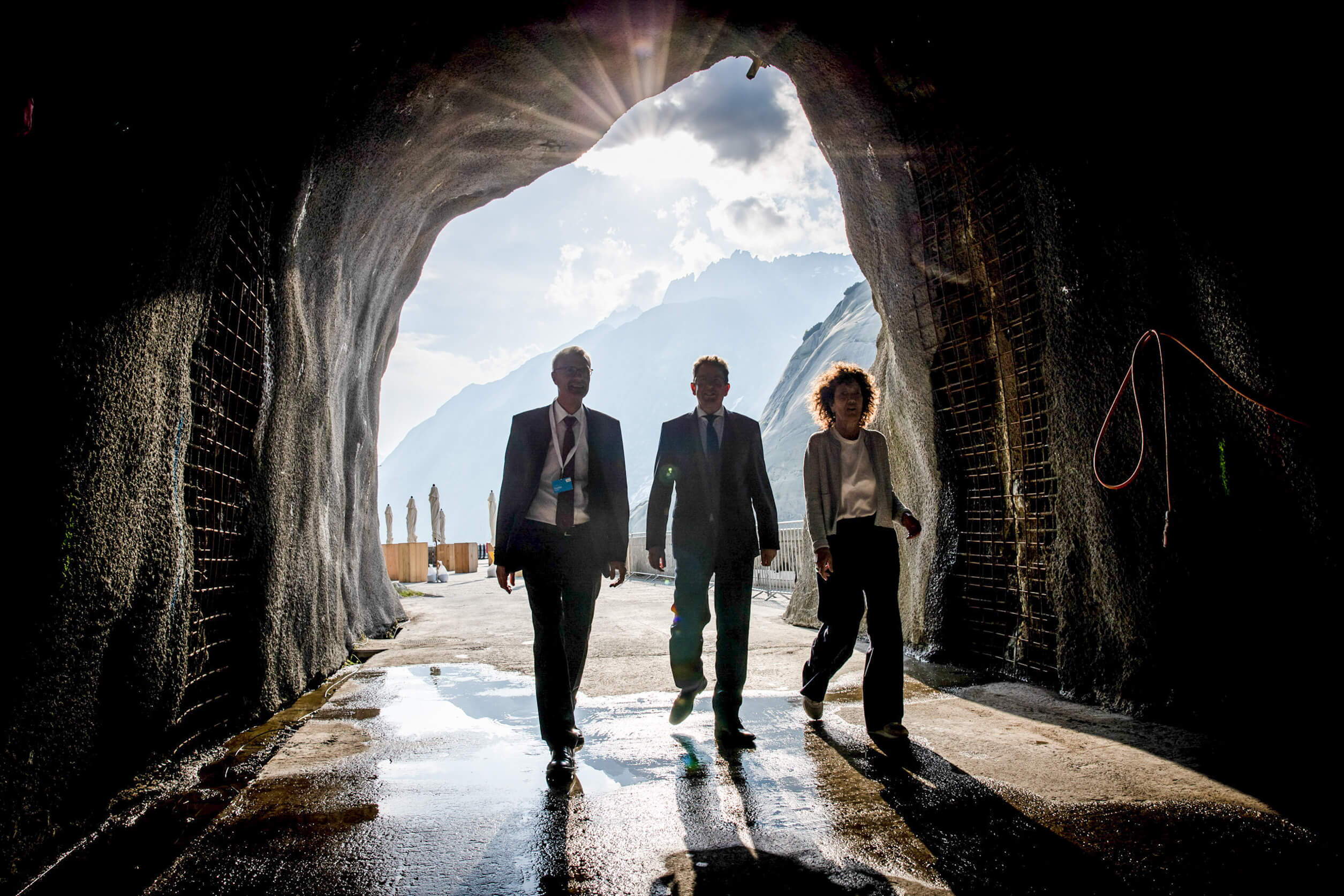 Gäste betreten durch einen Felsstollen das Eventgelände der KWO – Lichtstrahlen und Bergkulisse erzeugen eine eindrückliche Inszenierung.