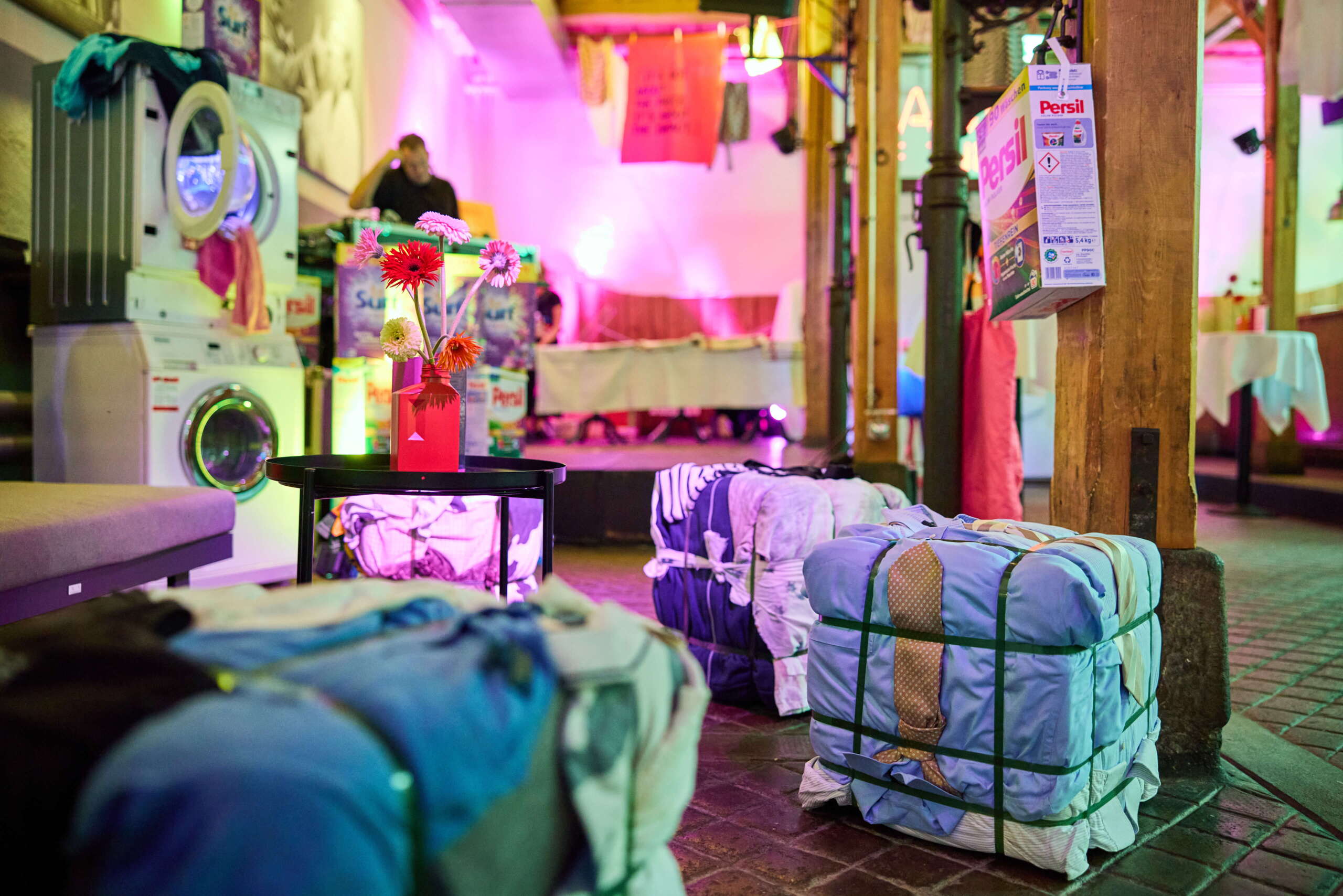evenjo_swisstextiles_jubilaeum-21.jpg Waschsalon-Setting mit DJ & Persil, Eventlocation im Stil eines Waschsalons mit DJ, Waschmaschinen und buntem Lichtdesign – kreative Inszenierung zum Thema Textil und Nachhaltigkeit. Textilindustrie, Eventdesign, Markeninszenierung, Swiss Textiles, markenerlebnis, Brand Experience, Riithalle Zürich, Dekoration, jubiläumsfeier, mitarbeiteranlass, live kommunikation