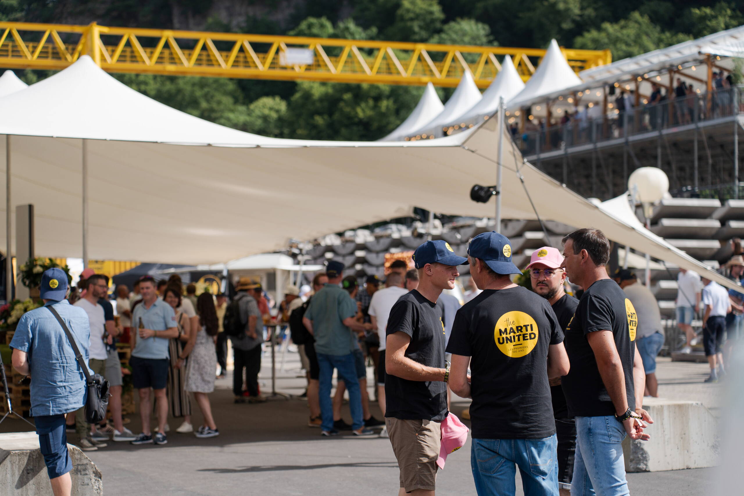 crossmediale-kommunikation-jubilaeum-marti-ag-4.jpg Besucherinnen und Besucher beim Marti United 100 Jubiläumsfest unter und vor weissem Zelt. Networking, Live-Kommunikation, Firmenjubiläum Markenerlebnis, Brand Experience, Mitarbeiteranlass, Live Kommunikation, Corporate-Event, eventplanung, Jubiläumsfeier, Mitarbeiteranlass, Teamevent, 100 Jahre Marti AG, Festival
