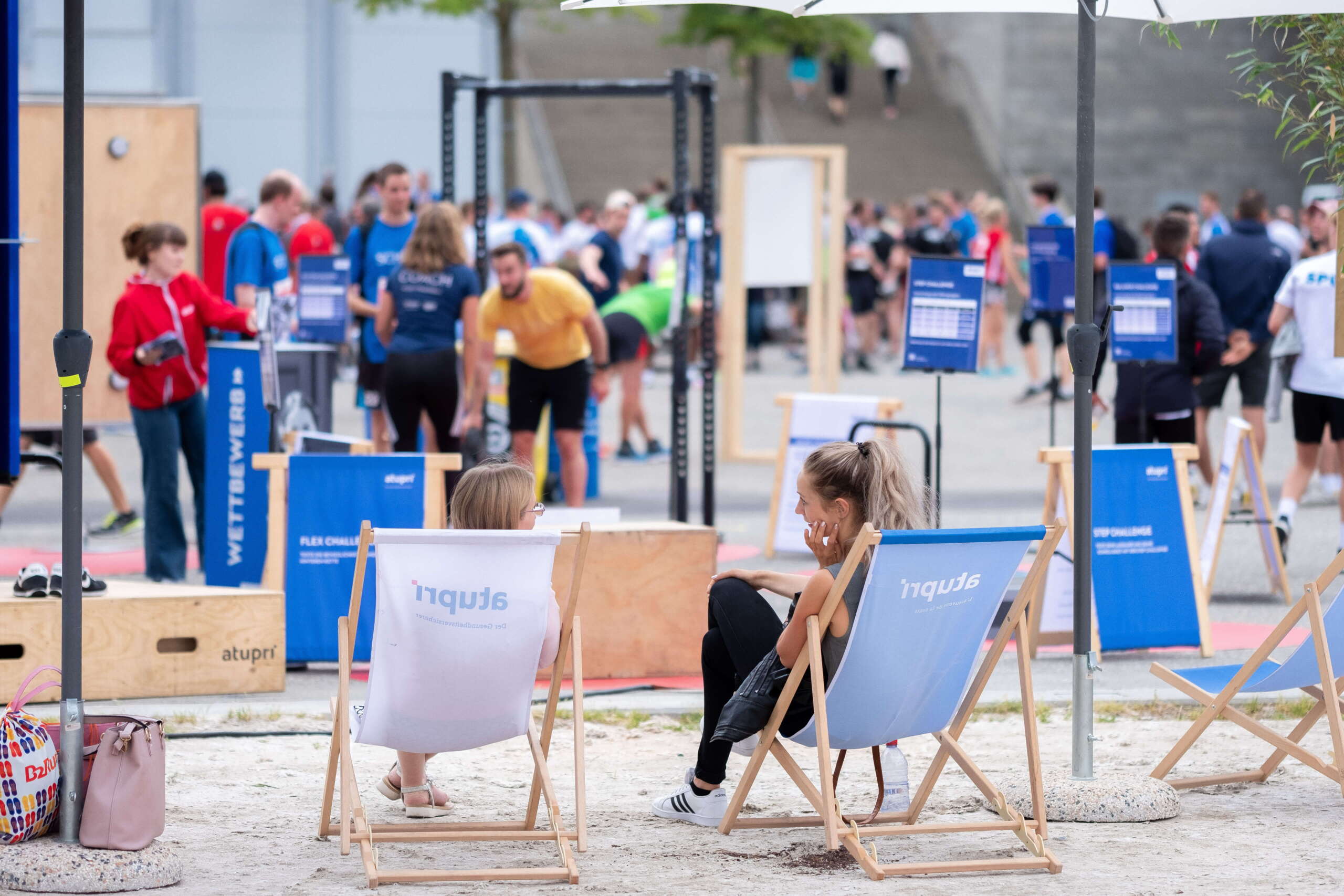 evenjo-ag-eventagentur-bern-atupri-healthbox-7.jpg Zwei Teilnehmerinnen entspannen sich nach dem Workout im Liegestuhlbereich der Atupri Healthbox beim Fitness-Event. Atupri Healthbox, Fitnesspause, Entspannung, Liegestühle, Gesundheitsevent, Wohlfühlen, live kommunikation, Corporate-Event, Eventagentur bern, eventplanung, firmenevents, teamevents bern, jubiläumsfeier, networking anlass, mitarbeiteranlass, Technik, Public Events, Sport und Entertainment Events, markenerlebnis, Brand Experience