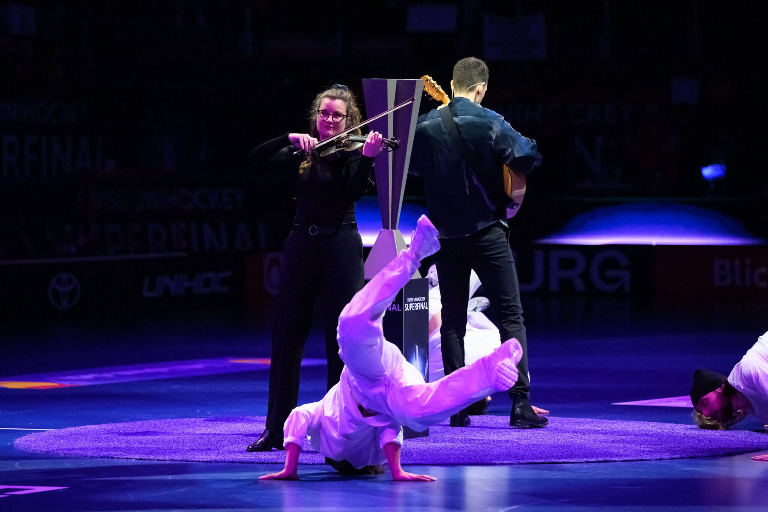 evenjo_superfinal_Swiss_unihockey_sport-event_eroeffnung.jpg Künstlerische Showeinlage beim Unihockey Superfinal: Violinistin und Gitarrist spielen live während Breakdancer performen in der BCF Arena in Fribourg. live kommunikation, Corporate-Event, Eventagentur bern, eventplanung, firmenevents, teamevents bern, jubiläumsfeier, networking anlass, mitarbeiteranlass, evenjo-Team, Technik, Public Events, Sport und Entertainment Events, markenerlebnis, Brand Experience, Corporate-Event