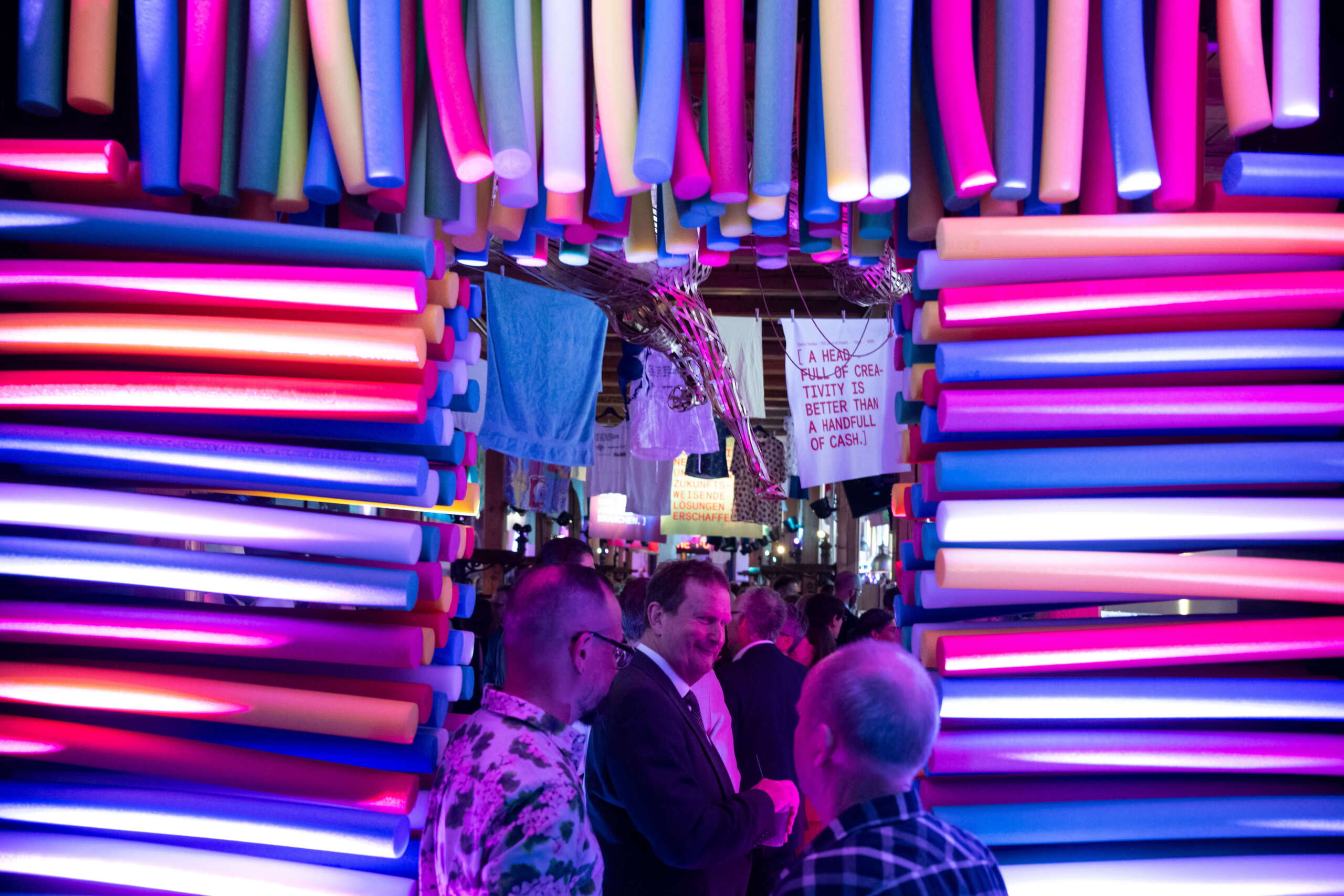 evenjo_swisstextiles_jubilaeum-48.jpg Farbenfroher Eingang aus Poolnudeln empfängt die Gäste – verspielter Einstieg in ein Event voller Kreativität und Textilkunst. Eventinstallation, Kreative Raumgestaltung, Textildesign, Erlebniswelt, Swiss Textiles Jubiläum, Firmenjubiläum, Waschen, Corporate-Event, eventagentur bern, eventplanung, markenerlebnis, Brand Experience, Riithalle Zürich, Dekoration, jubiläumsfeier, mitarbeiteranlass, live kommunikation, Texil-Branche