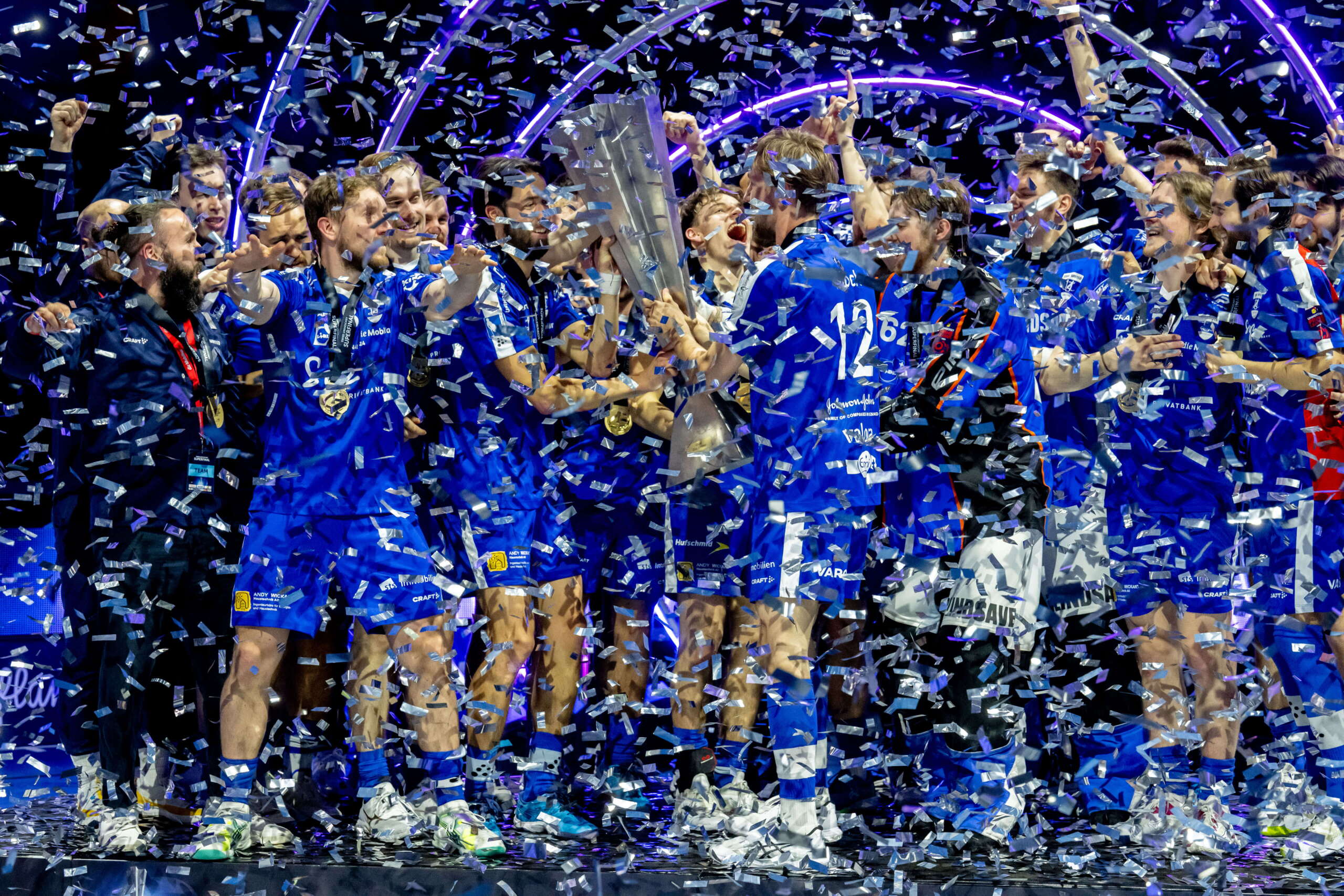 unihockey-superfinal-evenjo-ag-bern.jpg Das Siegerteam des Unihockey Superfinals feiert den Schweizer Meistertitel auf der Bühne mit Pokal und Konfettiregen.live kommunikation, Corporate-Event, Eventagentur bern, eventplanung, firmenevents, teamevents bern, jubiläumsfeier, networking anlass, mitarbeiteranlass, evenjo-Team, Technik, Public Events, Sport und Entertainment Events, markenerlebnis, Brand Experience, Corporate-Event, Lichtshow, Eröffnungsshow